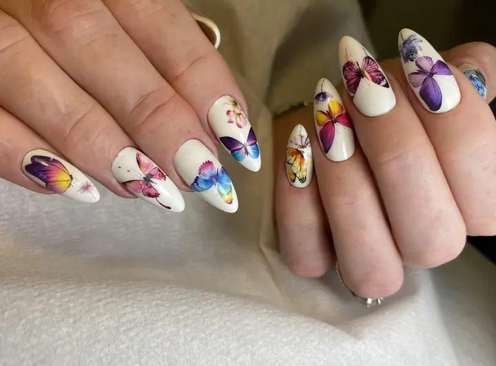 Hand-painted butterfly nail art on milky white almond nails