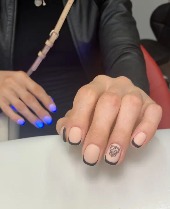 Nude manicure with black French tips and lace accent