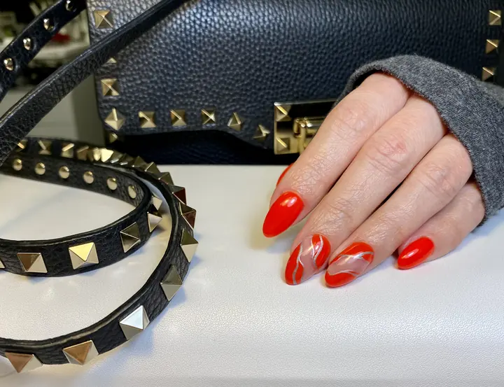 Red almond nails with white swirl accent