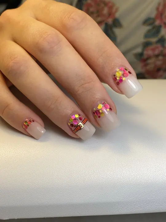 Nude manicure with confetti glitter accents